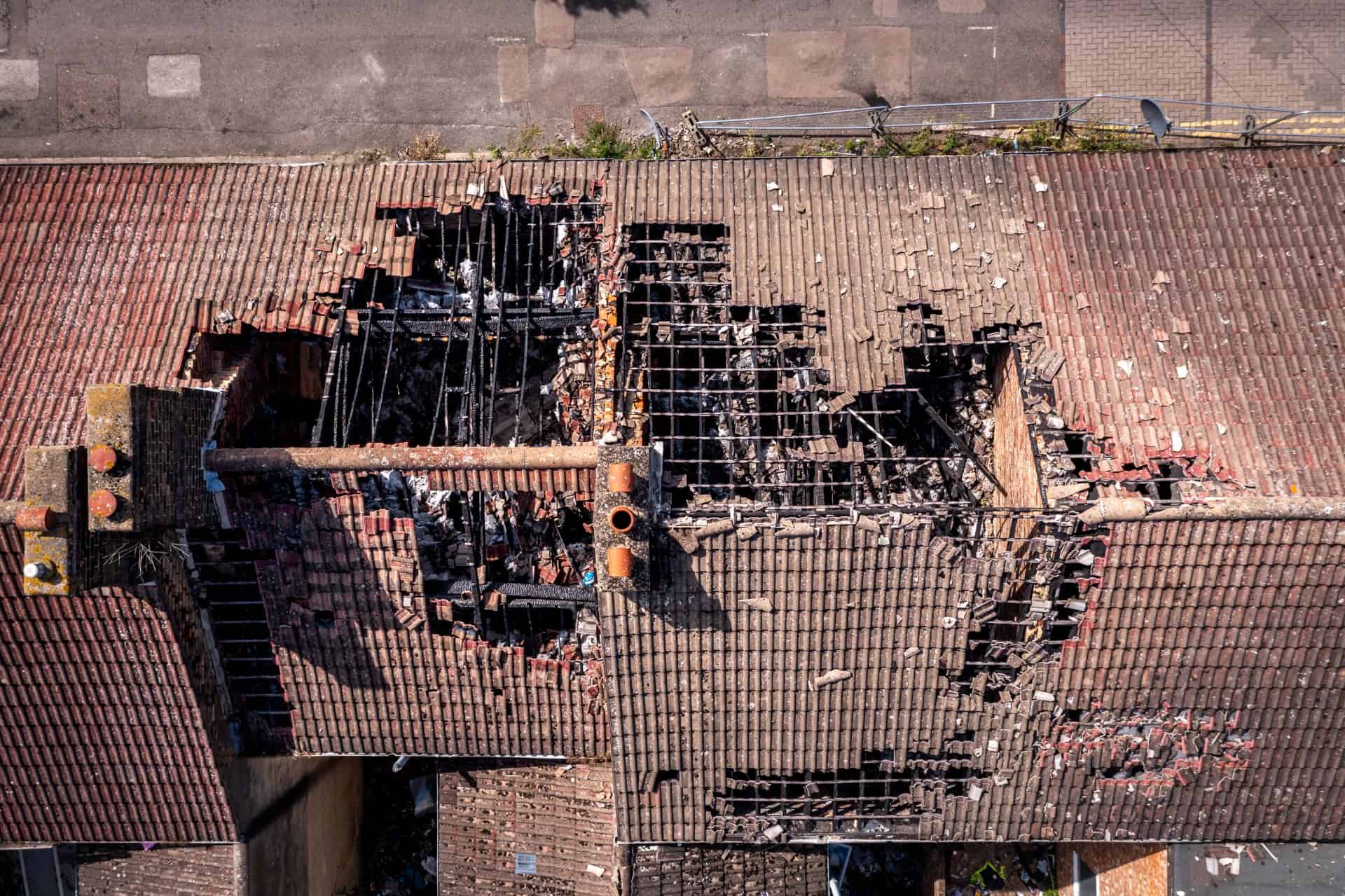 Aerial view directly above a row of burnt out and derelict terraced houses in the North of England with roof damage after a house fire